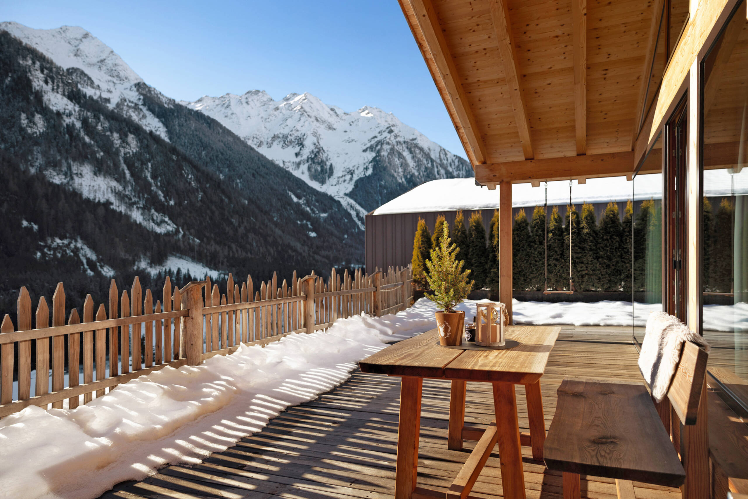 Terasse mit Holzbank und Tisch an einem sonnigen Wintertag - Gossa